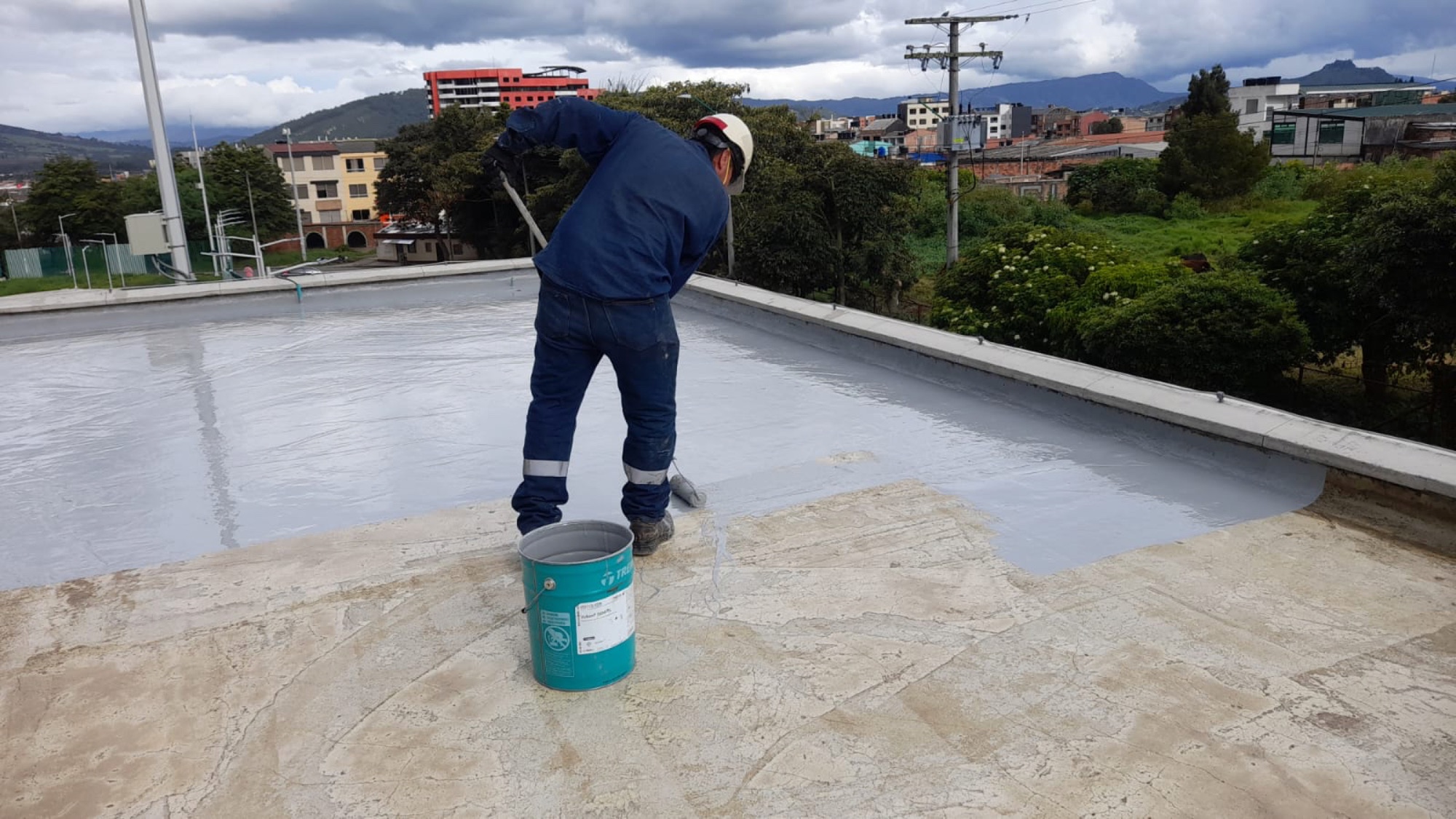 Técnico uniformado aplicando un sistema impermeable sobre una cubierta